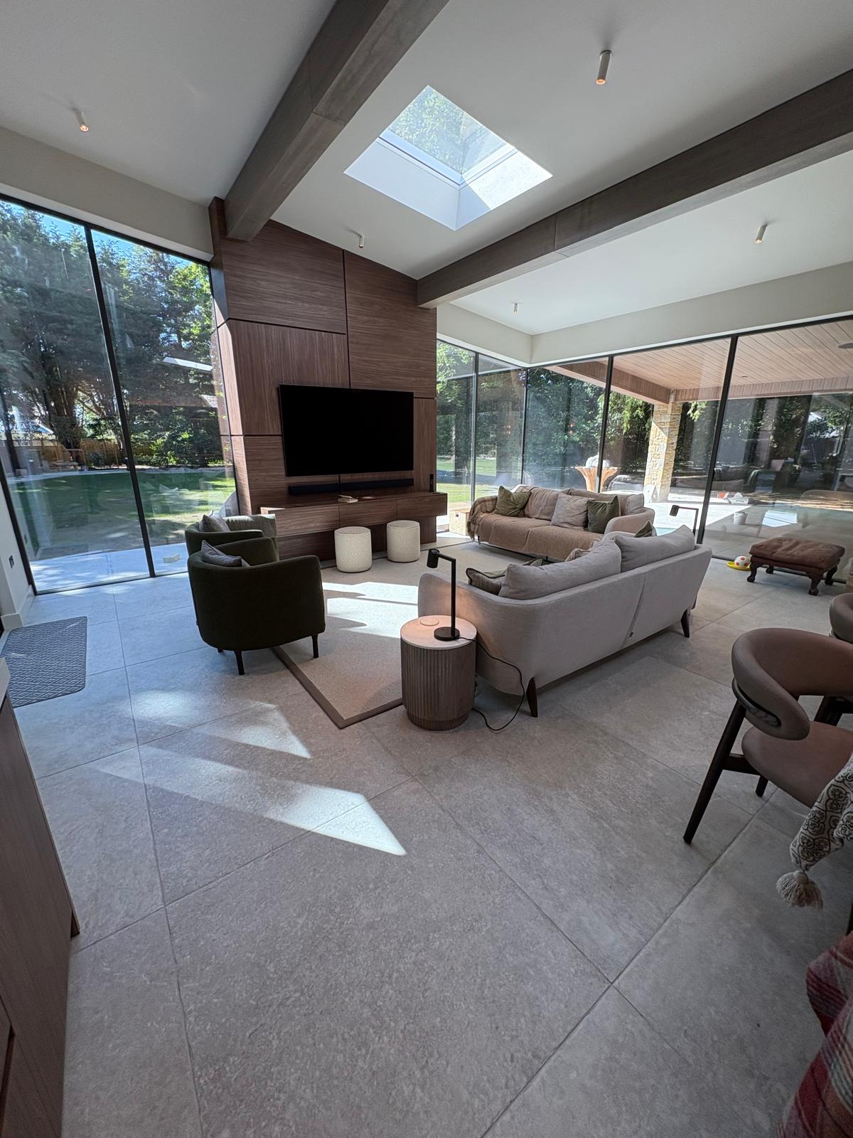 Open-plan living and dining space with large-format stone floor tiles and beamed ceiling